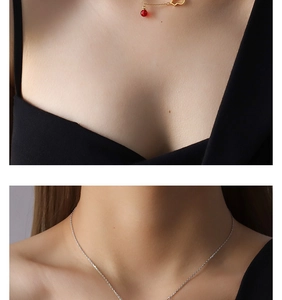 Close-up of a vintage-style gold chain necklace with a red bead and hollow heart pendant