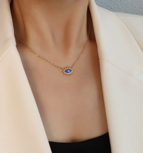 Nahaufnahme der goldenen Evil Eye Halskette mit blauem Zentrum auf einem Modell