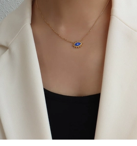 Nahaufnahme der goldenen Evil-Eye-Halskette mit blauem Emaille an einem Model im Anzug