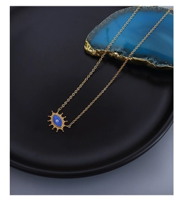 Makro-Detail des goldenen Evil-Eye-Anhängers mit blauem Email auf mattem schwarzem Display