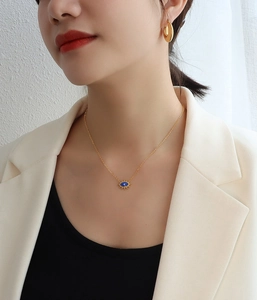 Nahaufnahme der goldenen Evil Eye-Halskette und strukturierten Creolen am Modell