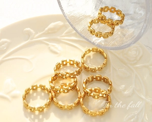 Macro detail of gold-plated hollow chain link rings displayed on a vintage plate