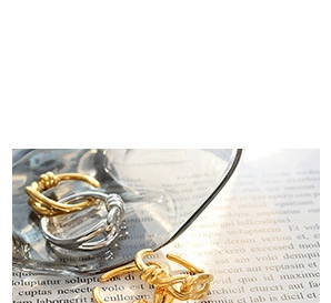 Detailed view of intertwined gold and silver twisted rings on a stylish glass background