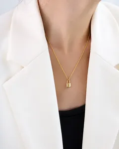 Minimalist gold lock pendant necklace worn by a model in a professional white blazer
