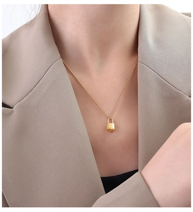 Detailed view of an 18k gold lock pendant necklace worn with a stylish blazer