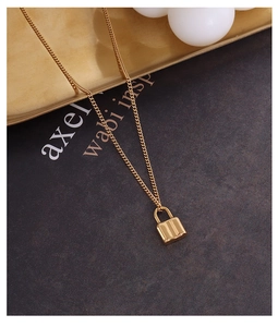 Macro shot of 18k gold plated padlock pendant on a curb chain with polished finish