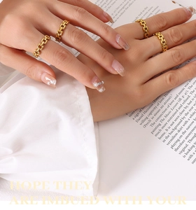 Detailed view of a four-piece set of gold chain rings worn on a woman's hand