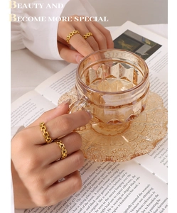Detail of gold chain link rings on hand holding glass with warm lighting backdrop