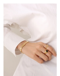 Nahaufnahme von goldenem Armband im Uhrenstil und schwarzem Emaille-Smiley-Ring