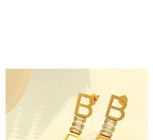 Macro shot of gold stud earrings featuring a hollow letter B design set with clear zircons