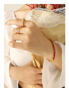 Detail of elegant gold honeycomb ring and red zircon tennis bracelet on model