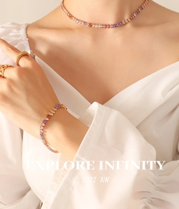 Detail of colorful oval gemstone necklace and bracelet set with golden stacking rings