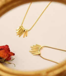 Detailed close-up of golden fringe pendant on snake bone chain with retro rose background