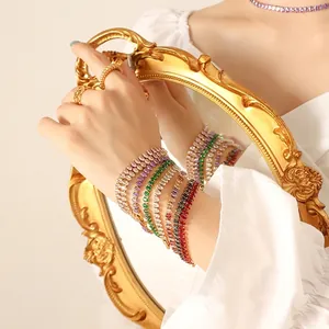 Elegant gold jewelry set with multi-colored gemstone bracelet and rings reflected in a mirror