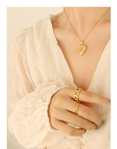 Collier à pendentif cœur doré associé à des bagues vintage portées par un mannequin