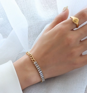 Detail of 18k gold plated chain bracelet with baguette zircon on model's wrist