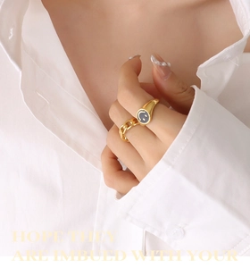 Close-up of golden smiley face signet ring and chain style ring set on model fingers