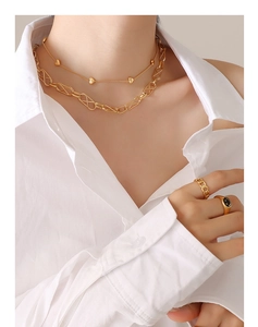 Detail of gold heart pendant and layered chunky chains with smiley face signet ring