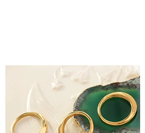 Macro shot of gold-plated irregular geometric lava style rings on a marble stone base