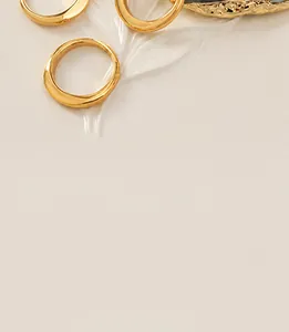 Close-up of three polished 18K gold plated stainless steel rings on a white display tray