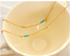 Détail d'une chevillère en acier doré avec perles turquoise et breloques ailes