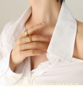 Detail of stacked gold rings featuring a smooth dome band and a Cuban chain link texture