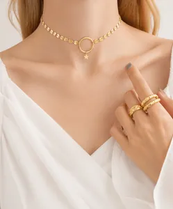 Dettaglio di una collana con ciondolo a stella dorata e anelli testurizzati su modella