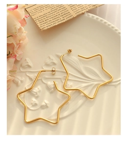 Macro shot of large star-shaped gold earrings on a vintage porcelain plate background