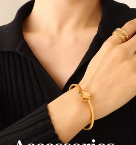 Close-up of elegant gold butterfly cuff bracelet and textured lava ring on model