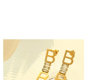Detalle de pendientes con la letra B dorada y tres circonitas verticales de corte baguette