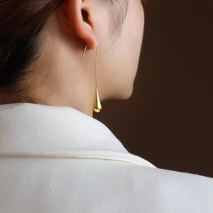 Minimalist gold teardrop earrings for women worn by a model in white formal attire