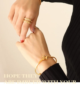 Detailed close-up of golden butterfly open bangle with zircon inlay on female wrist