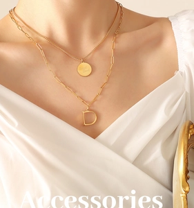 Detalle de collares a capas bañados en oro de 18K con letra D y colgantes Good Luck