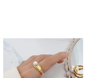 Detailansicht eines breiten vergoldeten Rings mit runder Perle am Finger eines Modells