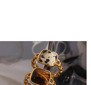 Makroaufnahme von Vintage Gold-Kettenringen mit Tigerauge und Marmorstein-Fassung im Detail