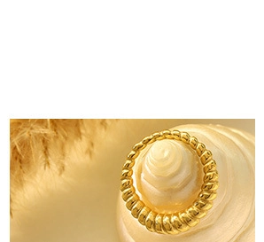 Nahaufnahme eines goldenen Croissant-Rings auf einer Muschel mit dekorativen Trockenblumen