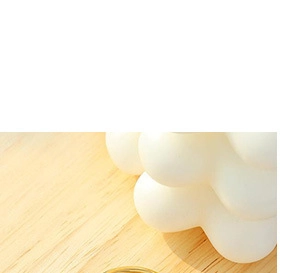 Detail eines Goldrings mit grünem Rund-Edelstein auf einer schlichten Holzoberfläche