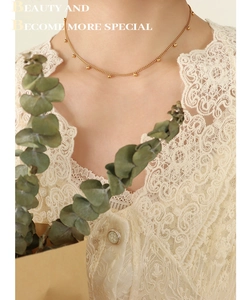 Nahaufnahme der minimalistischen Goldperlenkette am Hals mit französischem Vintage-Look