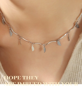 Primer plano del collar plateado de cadena irregular con pequeños dijes de hojas