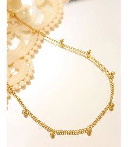 Nahaufnahme einer zweilagigen goldenen Perlenkette, die auf einem Spiegel mit Spitze reflektiert
