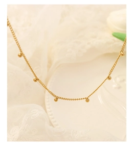 Detail einer eleganten Goldperlenkette mit kleinen Kugelanhängern an einer feinen Kette