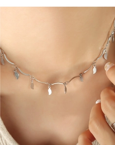 Primer plano de un collar de cadena con hojas plateadas en el cuello de modelo