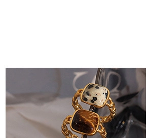 Vista macro de anillos de cadena dorados con mármol blanco cuadrado y piedras ojo de tigre