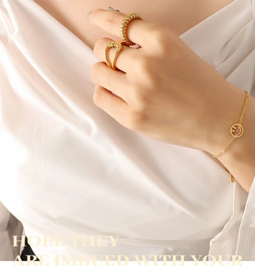 Nahaufnahme von goldenem Smiley-Armband und Stapelringen an einem weiblichen Model