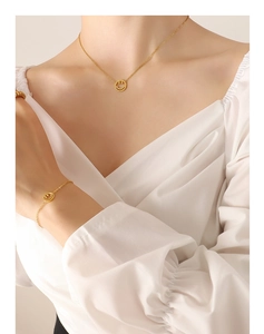 Nahaufnahme von goldenem Smiley-Halsketten und Armband-Set, getragen an Hals und Handgelenk