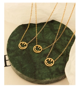Detailansicht von drei goldenen Halsketten mit hohlem Smiley auf einer Marmorplatte