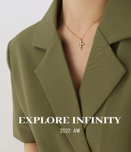 Gros plan d'un collier pendentif croix doré avec perles porté sur un blazer olive