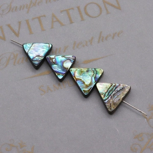 Macro detail of four triangular abalone shell beads with blue-green iridescent texture