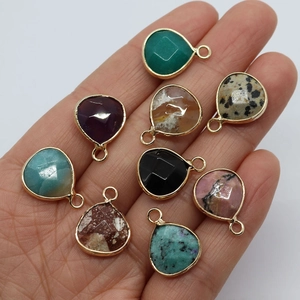 Natural teardrop stone pendants with gold-plated edges held in hand for DIY jewelry