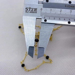 Medición de precisión de una cuenta negra de 4mm en cadena dorada con un calibre digital